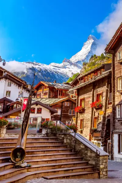Zermatt, Switzerland iconic town street view in famous Swiss Alps ski resort, Matterhorn snow mount, bronze alphorn and houses